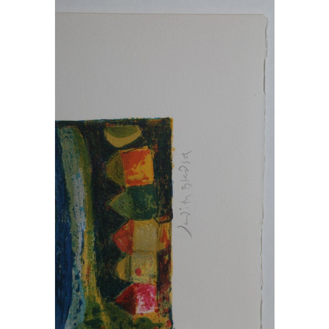 Soaring over the landscape, a bird in green and red feathers spreads it wings over the small town underneath it. Rendered...