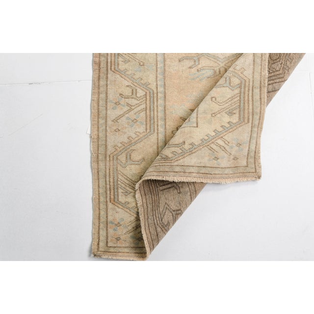 This is a vintage Turkish Oushak rug from the Mid 20th Century. The piece was hand-knotted.