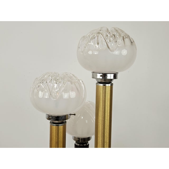 Elegant 1970s floor lamp with wooden and golden metal structure enriched by three Murano glass light points worked in the...
