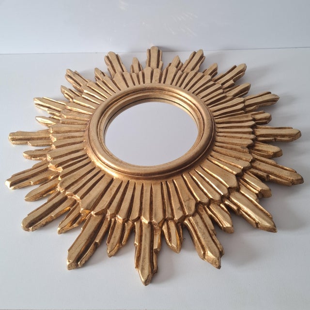 This striking mirror is designed in the shape of a stylized sun. The round mirror surface is located in the center and is...