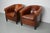 This pair of cognac-colored leather club chairs come from the Netherlands. They are upholstered with cognac-colored...