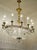 A large oval chandelier in the Empire style, richly decorated with crystals and brass inserts that enhance its decorative...