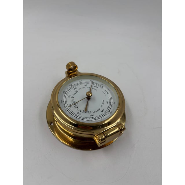 Decorative weather station with barometer, thermometer, and presumably hygrometer in round metal instruments, mounted on a...