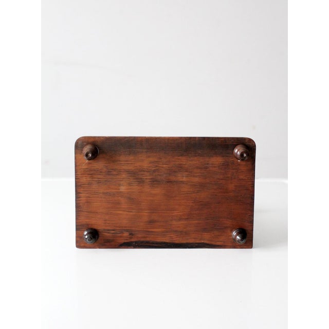 Early 20th century antique wooden vanity mirror with a warm-toned wood frame, turned uprights, and a gently tilting oval...