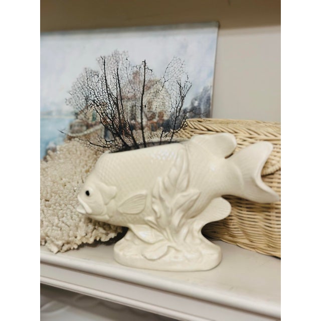 This is a vintage ceramic fish-shaped planter or cachepot with a sculptural underwater motif. It features a creamy white...