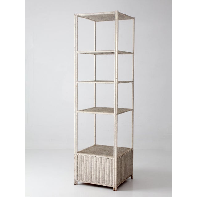 Beautiful vintage white wicker étagère dating to the 1960s–1970s, showcasing a charming blend of Coastal and Hollywood...