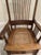 Beautiful vintage high-backed oak rocking chair featuring hand-carved floral details, a woven cane seat, and gracefully...