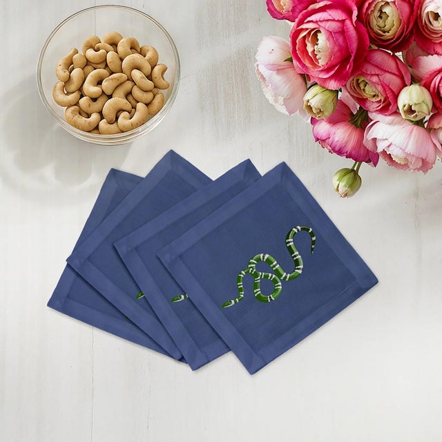 Serpent Cocktail Napkins feature entwined snake patterns that symbolize mystery, transformation, and strength. Designed in...