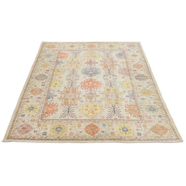 This rug features a sophisticated palette of faded apricot, sage green, and muted lavender on a neutral ivory background,...