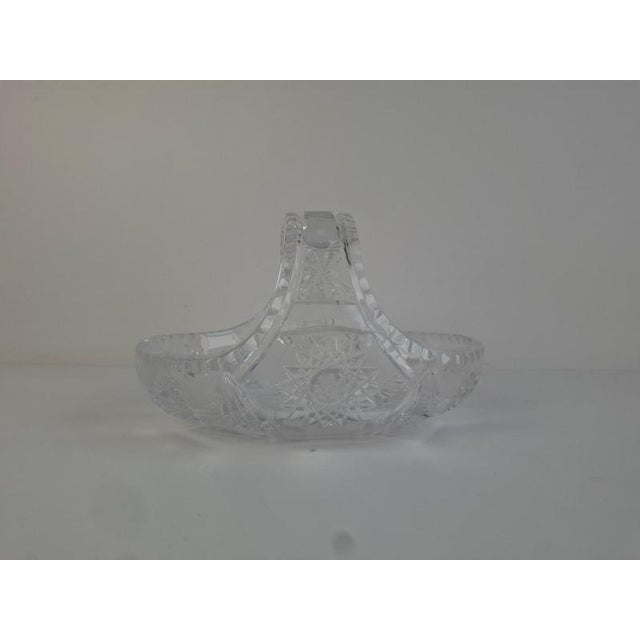 A mid-century cut crystal basket produced in Czechoslovakia, featuring deeply engraved starburst motifs and a sculpted...