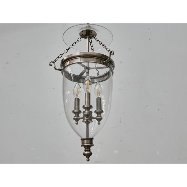 An elegant English bell jar lantern in polished nickel, dating to the mid-20th century and distinguished by its refined...