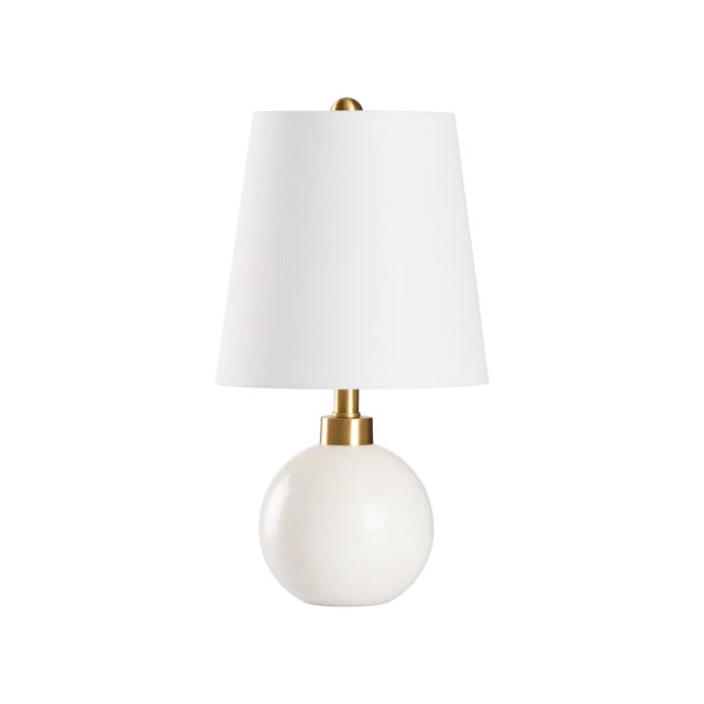 This matte white lamp features decorative orbs along the sides, adding a sculptural touch to its sleek, modern design....