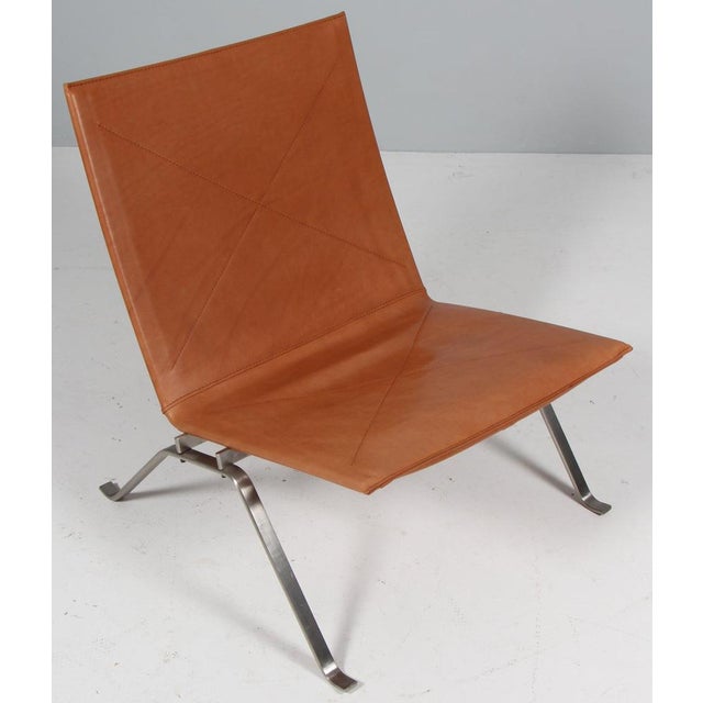 Poul Kjærholm lounge chair in patinated tan leather. Frame of brushed steel. Model PK22, made by Fritz Hansen. This piece...