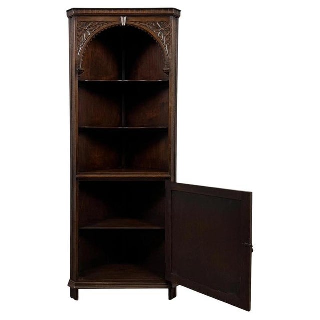 A handsome early 20th-century English corner cabinet, finely crafted from oak and distinguished by its richly carved...