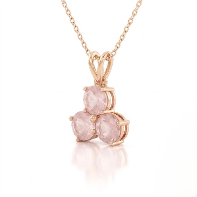 A romantic three-stone design featuring round-cut natural rose quartz arranged in a graceful trefoil formation, secured in...