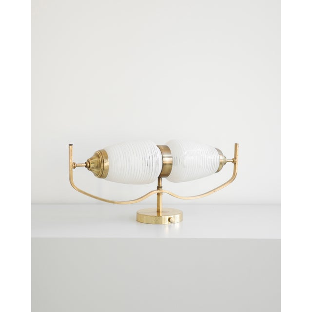 Two elegant lamps of French origin. Each features a brass frame and two white shades adorned with a subtle stripe. Both...