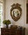 A Federal-style giltwood convex mirror crowned with a carved eagle, its wings outstretched above a laurel motif—an...