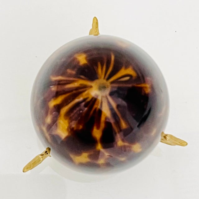 Elegant decorative egg crafted in richly colored tortoiseshell-style art glass, presented on an ornate gilt metal stand...