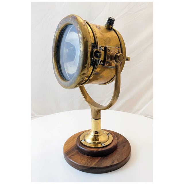 Vintage 1930's brass yacht search light mounted on a walnut base. The light has a handle on the back to move the light up...
