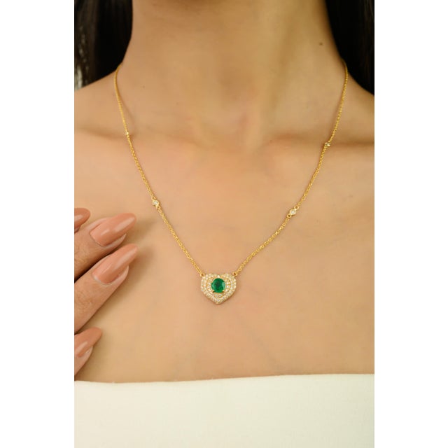 This refined heart pendant necklace features one vibrant round-cut natural emerald totaling 0.66 carats, crafted in 14K...