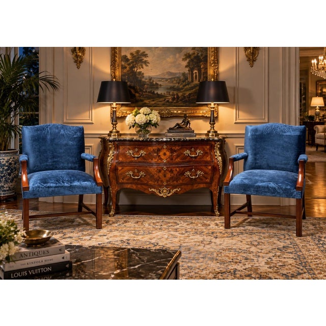 These are a matched pair of classic Regency style armchairs featuring exposed mahogany frames and rich blue velvet...