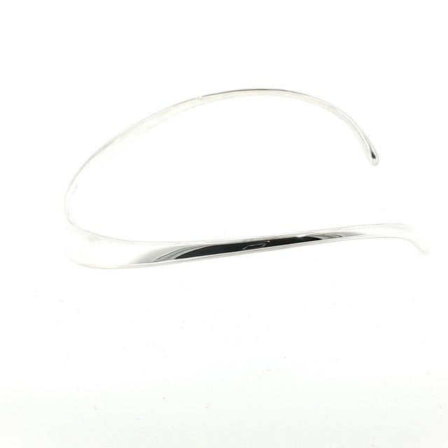 A sterling silver neck ring by David-Andersen for Tiffany & Co. This features a sleek, curved design with an open back....