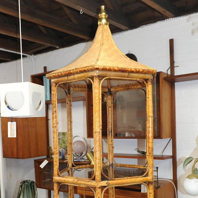 A striking mid-century étagère crafted in bamboo, crowned with an elegant woven pagoda-form bonnet that gives the piece an...