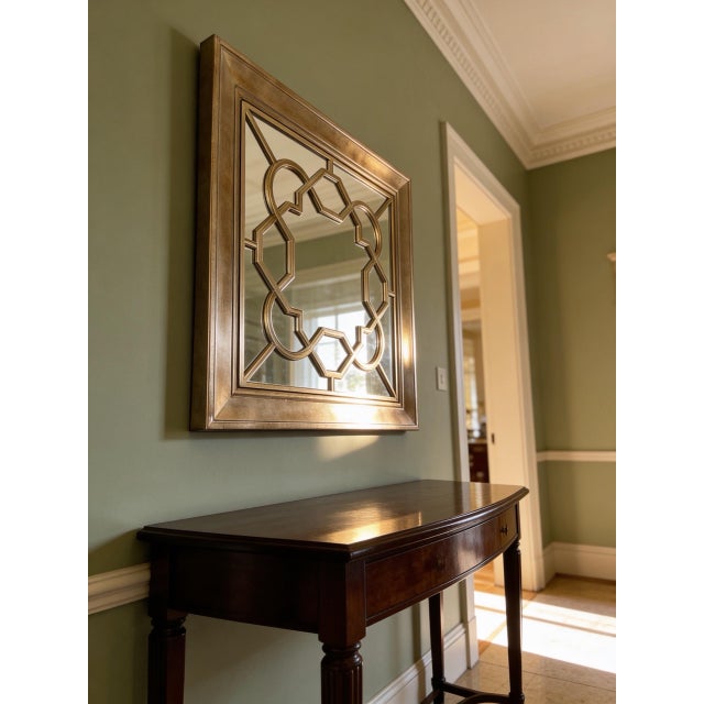 Uttermost Piazzale wall mirror in antique gold finish. Square shape with geometric overlay frame design. Wall-mounted...