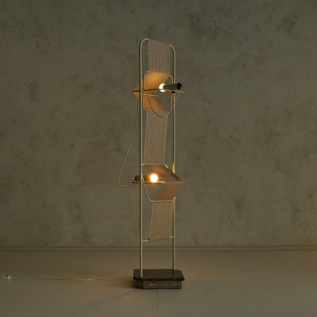 An Italian postmodern floor lamp from the 1980s, pairing an architectural ivory-enameled metal frame with a stepped base...