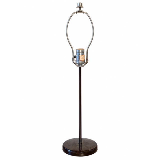 A beautifully understated vintage-style table lamp featuring a slender dark brown metal column, circular pedestal base,...