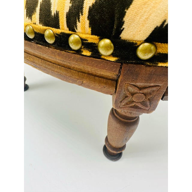 This is a stunning antique wooden footstool featuring updated upholstery that adds a bold and modern flair to its classic...