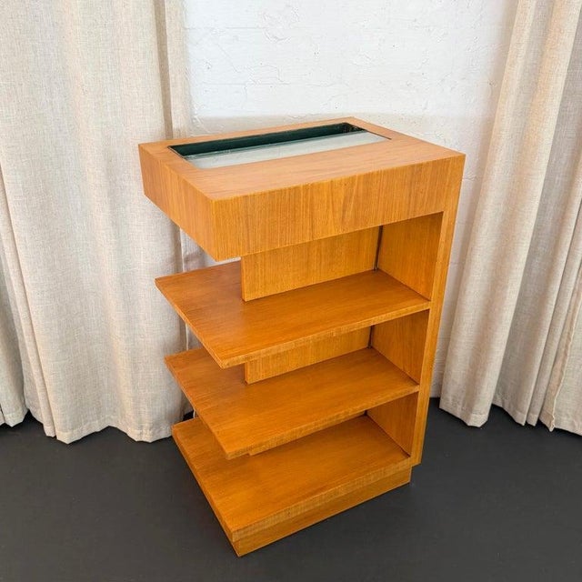 This Art Deco tiered satinwood shelving unit circa the 1940s is a unique piece that provides storage, display and light....