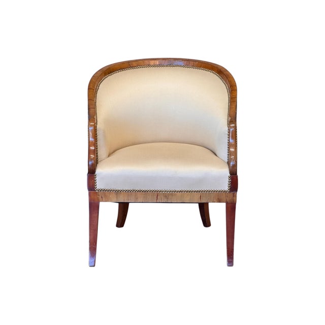 Biedermeier tub chair with a continuous curved fruitwood crest rail sweeping into shaped arm supports, the terminals...
