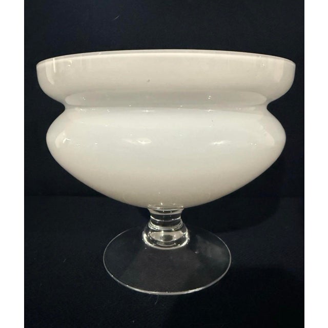 An elegant vintage pedestal bowl by Orrefors, crafted in luminous white opaline glass with a clear glass stem and foot....