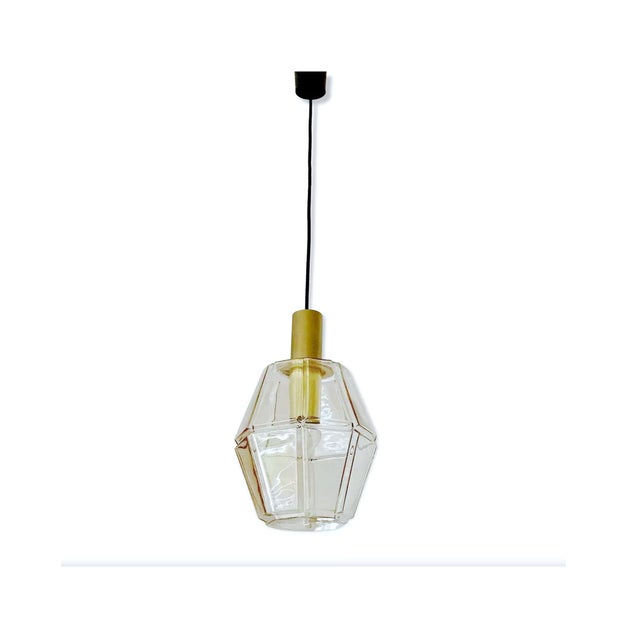 Large pendant light by limburg, featuring an oversized polyhedral glass shade with highlighted edge, polished brass...