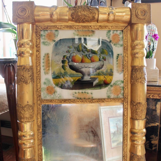 An unusually colorful and ornamental New England Sheraton mirror with wonderful bright gilding; this mirror features a...