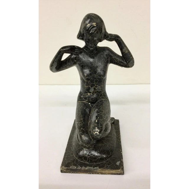 A simple nude cast metal pose of a young woman. The paint has begun to peel off. As long as the sculpture is not handled...