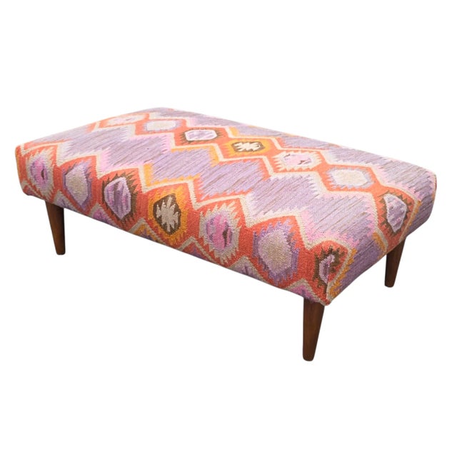 This Mid-Century Handwoven Kilim Upholstered Ottoman has artisanal and Mid-Century form, covered in a vibrant fabric - an...