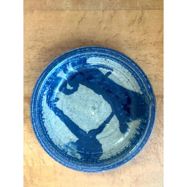 This vintage stoneware bowl is hand-thrown with a shallow, gently sloping profile and a slightly irregular, organic rim...