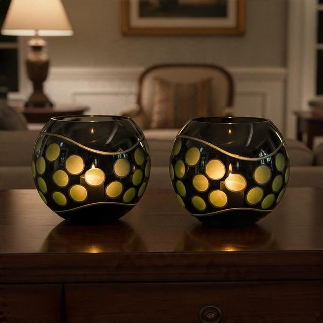 Pair of oversized vintage black glass globe candle holders featuring frosted green circular cutwork, polished reflective...