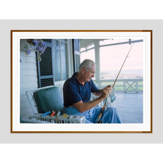 Howard Cushing by Toni Frissell Howard Cushing attaches fishing lure to his rod whilst relaxing on a porch in Newport,...