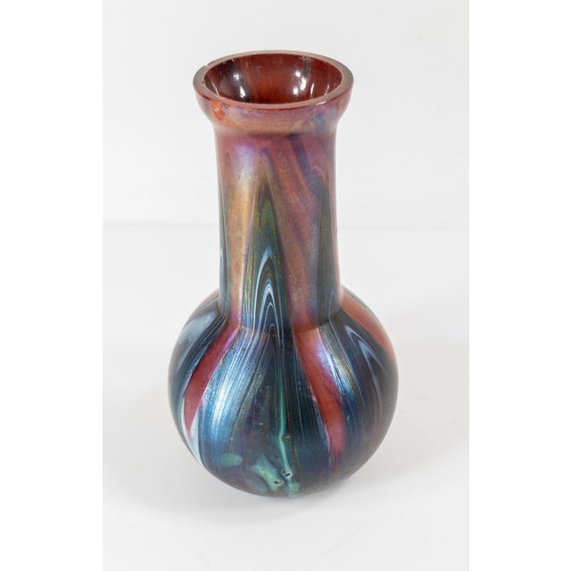 We are selling this Bohemian Loetz style art glass vase with red and purple swirled design. There is an old Barney’s label...