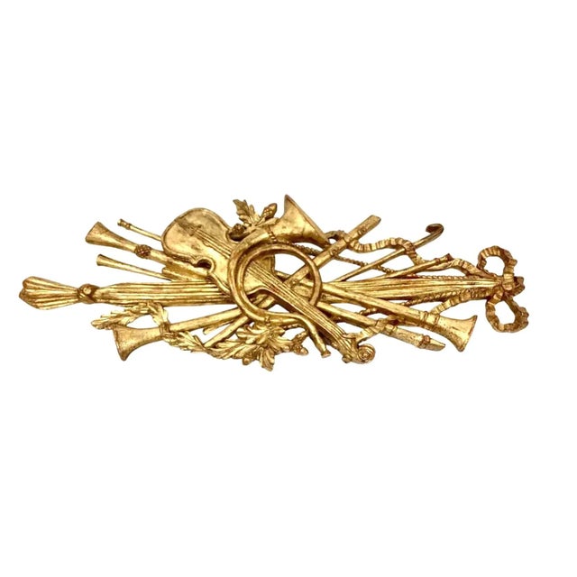 Vintage Palladio giltwood wall hanging of multiple musical instruments (violin, flute, horns) crested with large bow. Has...