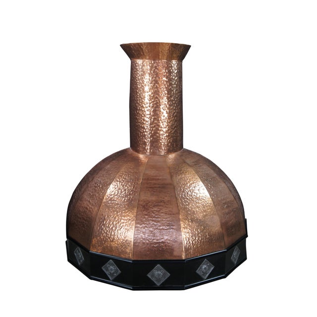 Vintage hammered copper range hood featuring a wide rounded dome base with geometric accents. and tall cylindrical...
