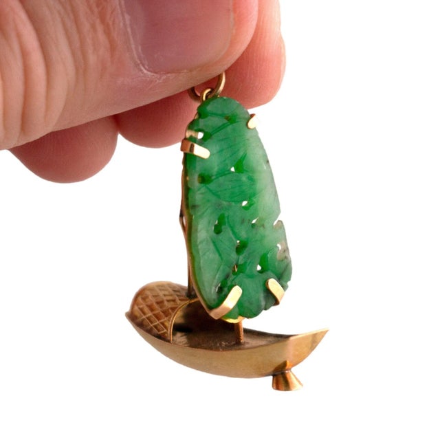 A vintage sailboat charm. Crafted from 18k yellow gold, it features a detailed basket weave design. The sail is adorned...