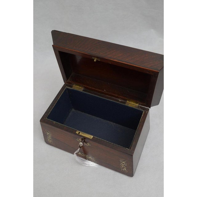 Attractive rosewood jewellery box with decorative scroll inlays, lined interior and original working lock with a key. This...