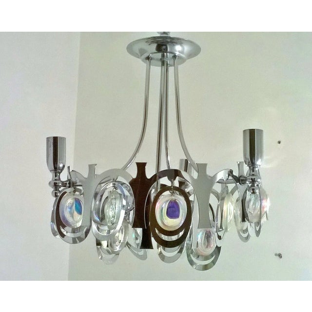 This chrome-plated steel chandelier, with four-light fittings and a many of glass sphere from rainbow-colored reflexes is...