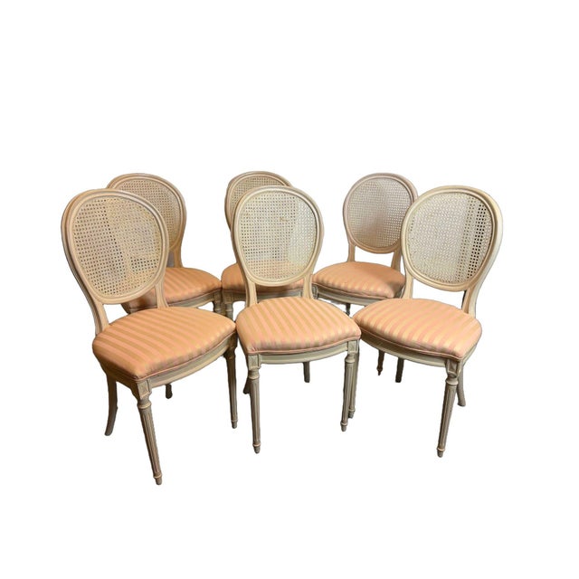 An elegant yet fun set of six vintage French Louis XVI style dining chairs dating to the 1970s, featuring classic oval...