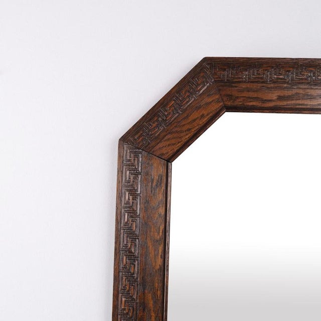Rectangular mirror with a carved dark oak frame dating from the 1940s. It features classic decorative details and is...