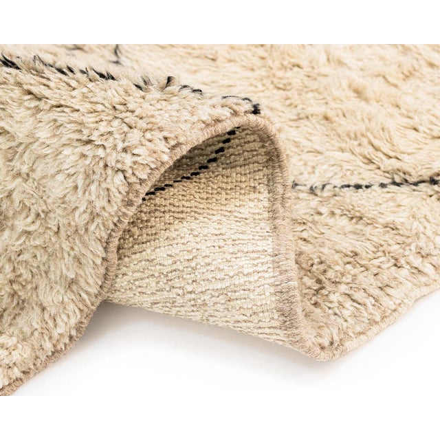 Earthy hand-knotted rug in an Oatmeal Beige color adorned with diamond patterned Charcoal lines. Its soft texture and...